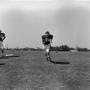 Photograph: [Football player #74 jogging center frame and #62, Bob Tricks, standi…