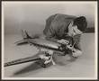 Photograph: [A technician readying a model of a DC-3 airliner]