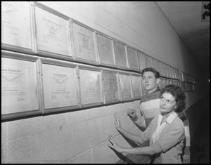 Primary view of object titled '[Two students looking at wall of awards]'.