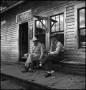 Photograph: [Two men chatting on a porch]