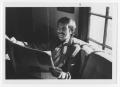 Photograph: [Bill Nelson smiling over a paper]