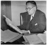 Photograph: [George A. Hill, Jr. sitting at desk reading book]