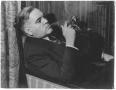 Photograph: [George A. Hill, Jr. leaning back in armchair, cigar in hand]
