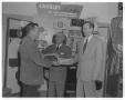 Photograph: [Men standing in front of radio display in store]