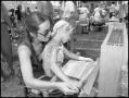 Photograph: [Woman Weaving on a Loom with a Child in Her Lap]
