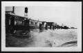 Photograph: [Stores along the dock. Location unknown.]
