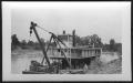 Photograph: [Boat near the bank of a river. Location unknown.]