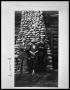 Photograph: Two Men with Woman in Front of Stone Chimney on Cabin