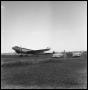 Photograph: [Airplane in a Field with Three Cars and People]