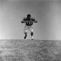 Photograph: [Football player #70, Jimmy Franklin, runs forward arms in a T]