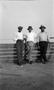 Photograph: [Three Men Stand in Front of a Railing]
