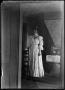 Photograph: [Posed young woman viewed through a doorway]