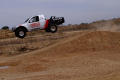 Photograph: [Truck going airborne after going over a dirt mound]