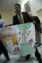 Photograph: [Sigifredo Munoz holds a large drawing in his hands]