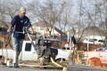 Photograph: [Man in blue shirt pushing heavy equipment]