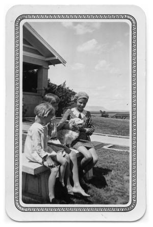 Girls sitting on a bench with a dog