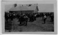 Photograph: [People gathering around a house]