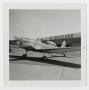 Photograph: [Airplane in Front of Hangar]