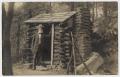 Postcard: [Postcard with Old Man Leaning on a Log Cabin]