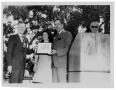 Photograph: [Two Men Hold a Framed Certificate in Front of Lady Bird Johnson]